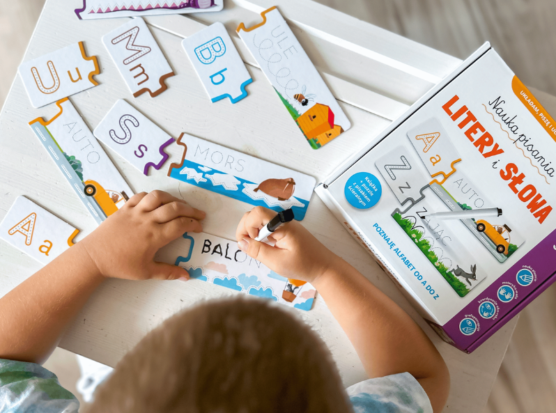 Chłopiec uzupełnia napis BALON, układając puzzle Nauka pisania. Litery i słowa. Książka + puzzle do pisania