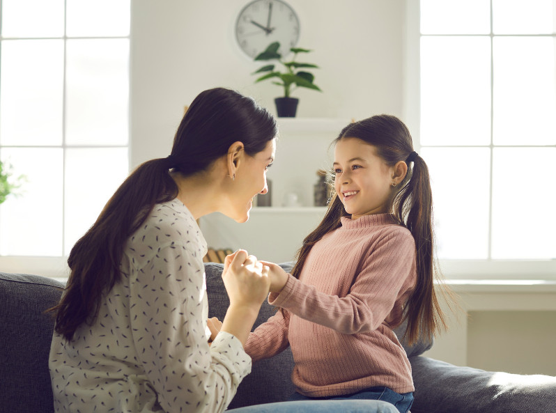 Dziewczynka uśmiechnięta patrzy na swoją mamę.