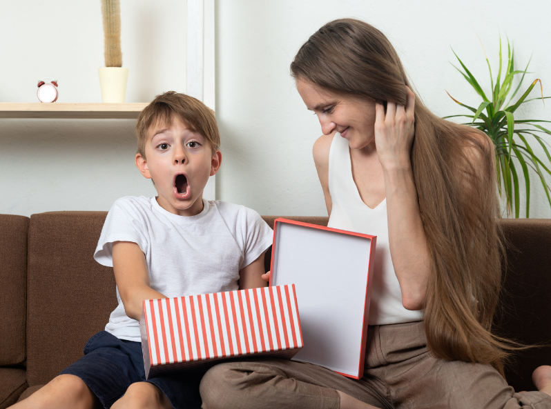 zaskoczony chłopiec otwiera prezent wielkanocny od swojej mamy