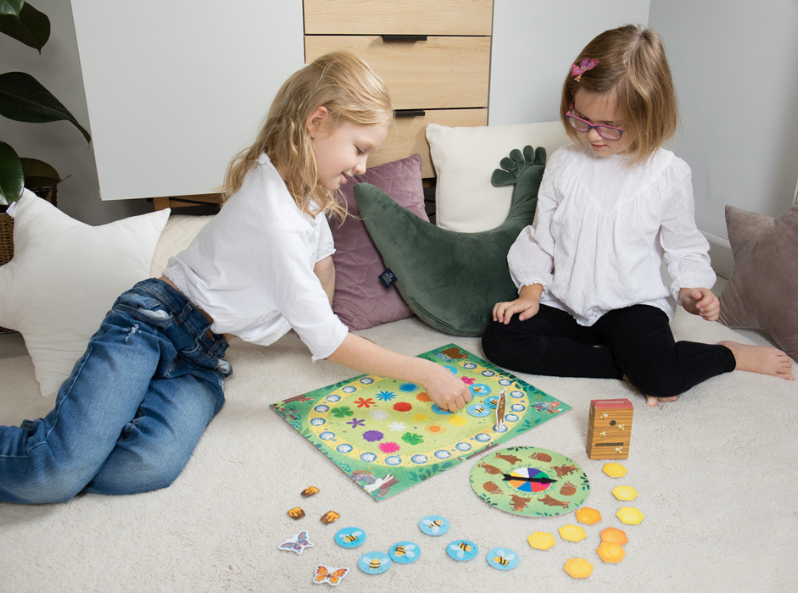 Dwoje dzieci gra w kooperacyjną grę planszową Miś i pszczoły