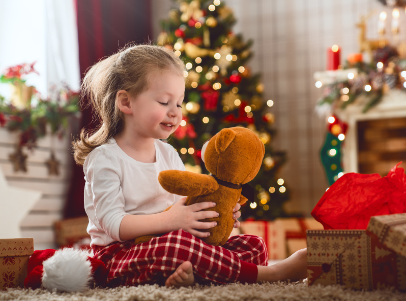 dziewczynka bawi się misiem podczas Świąt Bożego Narodzenia
