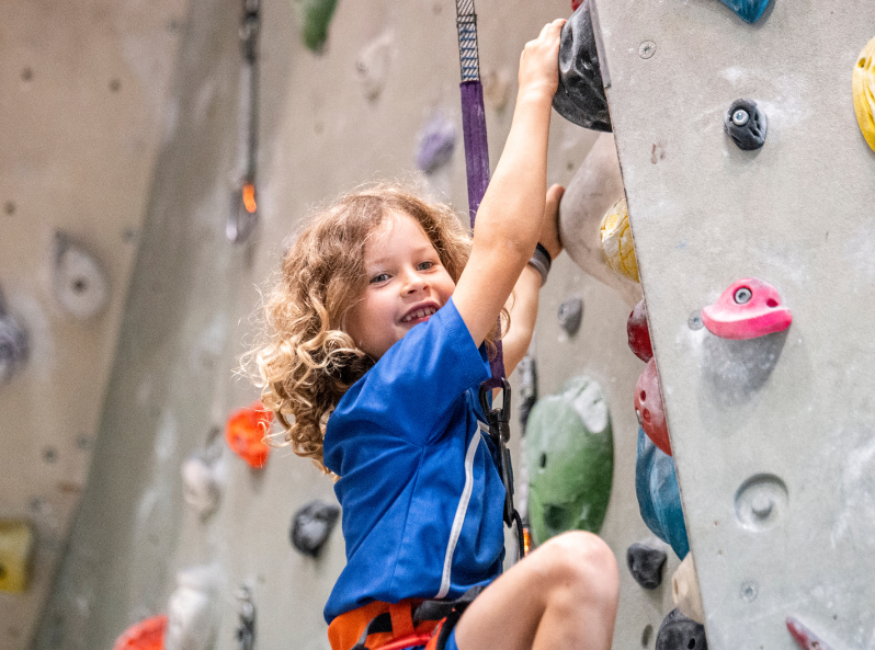 Dziewczynka wspina się po ściance wspinaczkowej