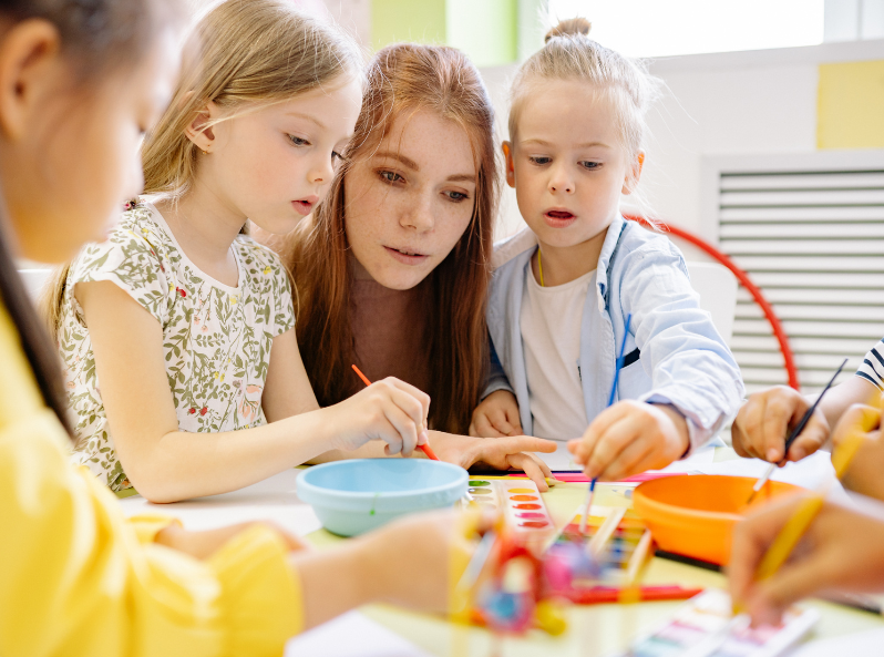 przedszkolaki i nauczycielka malują farbami motyle