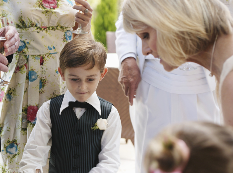 chłopiec na weselu stoi w gronie rodziny