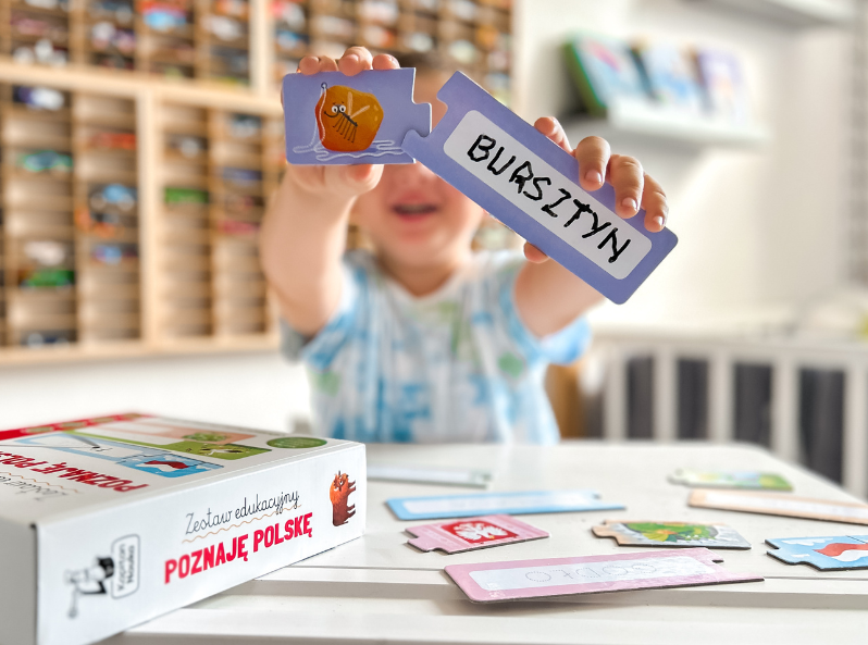 Chłopiec pokazujący puzzle z obrazkiem bursztynu