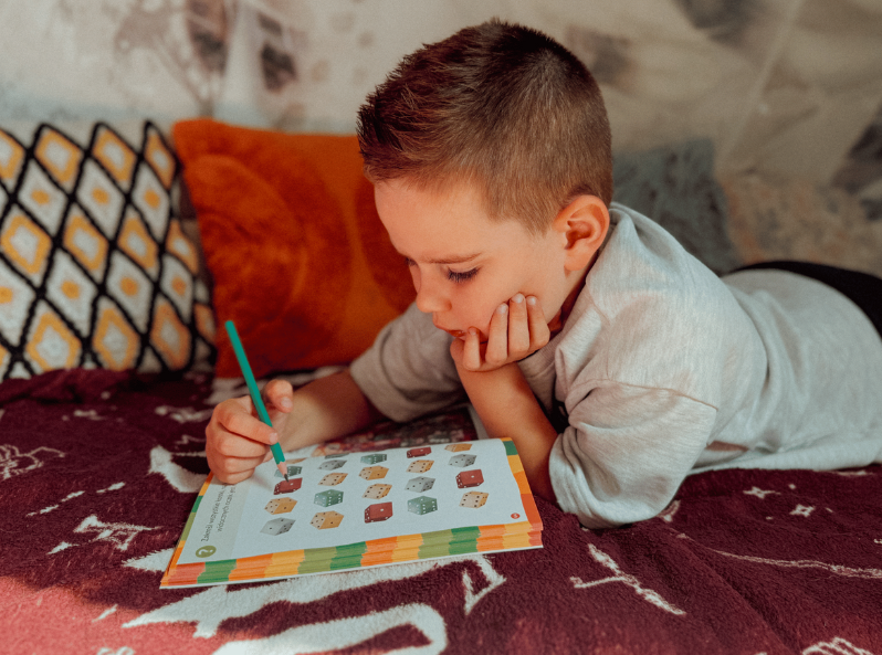 Skupiony chłopiec rozwiązuje Łamigłówki dla 6-latka" 