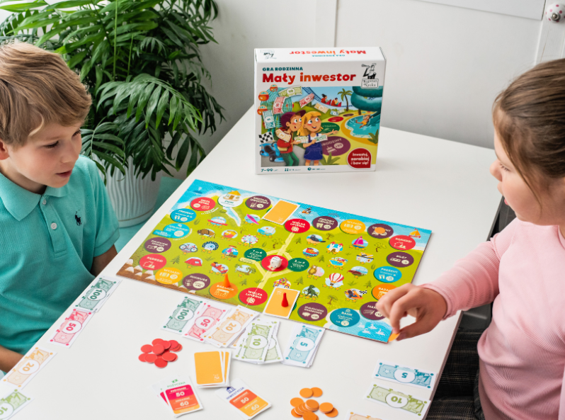 Dwoje dzieci gra w grę planszową o zarządzaniu finansami – Mały inwestor Kapitana Nauki