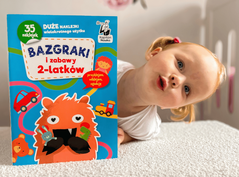 Dziewczynka trzymająca książeczkę Bazgraki I zabawy 2-latków