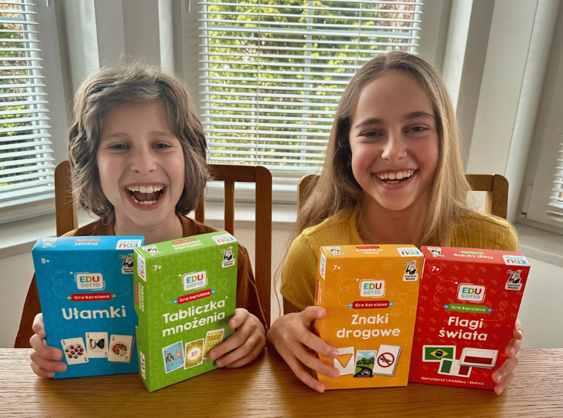 Dzieci trzymają gry karciane EDUseria - Tabliczka mnożenia, Ułamki, Flagi świata i Znaki drogowe